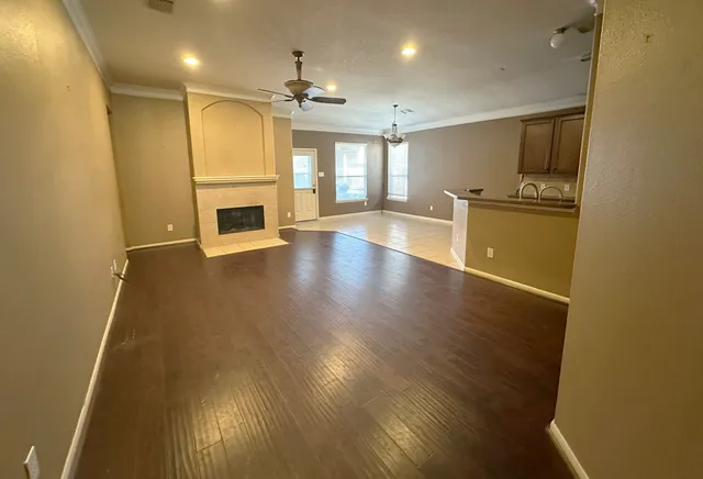 a view of an empty room with wooden floor and a fireplace