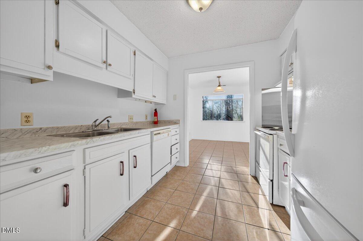 3088 Colony Road, Unit 3088D Durham, NC 27705 - Photo 7 of 25 a large white kitchen with granite countertop a sink