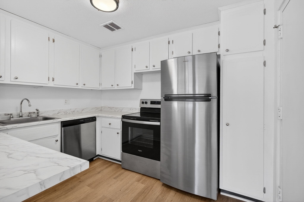 A1 Colonial Drive, Unit 10 Andover, MA 01810 - Photo 3 of 18 a kitchen with stainless steel appliances granite countertop a refrigerator sink and white cabinets