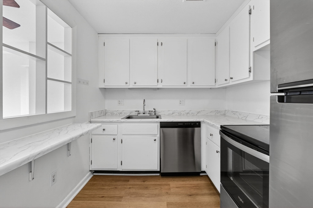 A1 Colonial Drive, Unit 10 Andover, MA 01810 - Photo 4 of 18 a kitchen with granite countertop white cabinets and white appliances