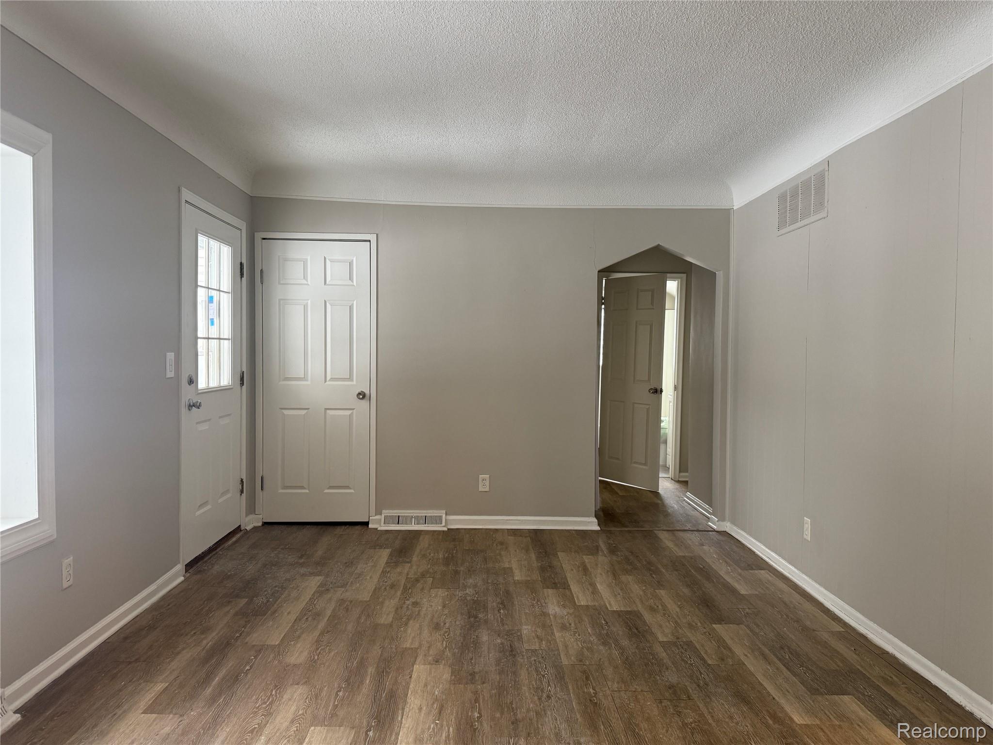 6237 Inkster Road Taylor, MI 48180 - Photo 8 of 14 Wood-finish flooring, light grey wall paint, white trim, paneled interior doors, and an arched doorway
