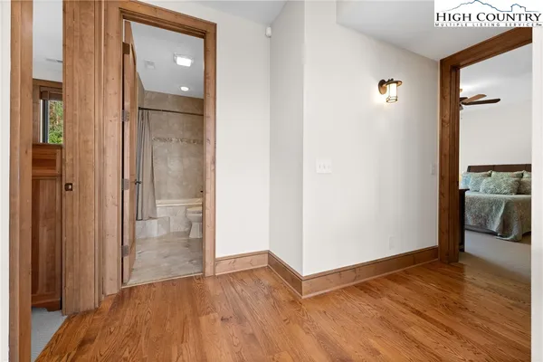 a view of a hallway with wooden floor and a bathroom