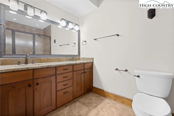 a bathroom with a granite countertop toilet sink and mirror