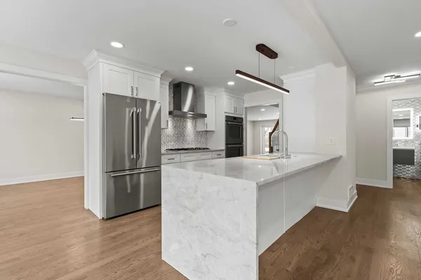 a kitchen with stainless steel appliances white cabinets and wooden floors