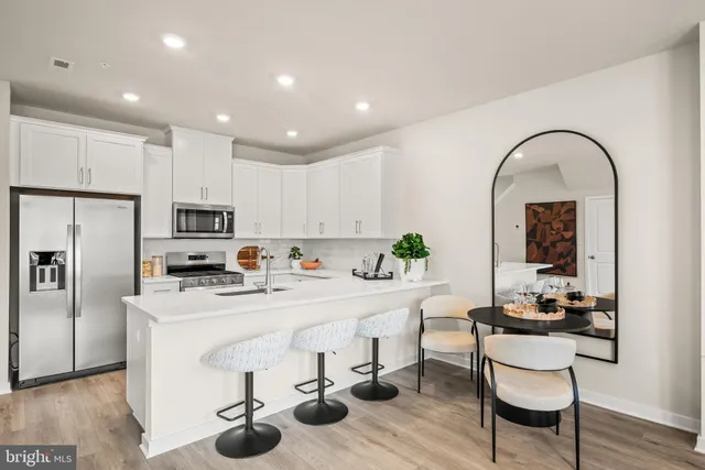 a kitchen with stainless steel appliances granite countertop a table and chairs in it