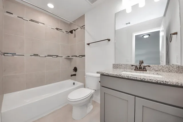 a bathroom with a granite countertop sink a toilet and shower
