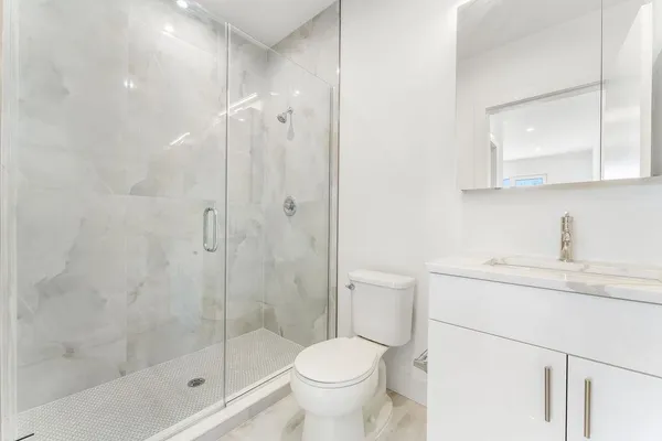 a bathroom with a granite countertop sink toilet and shower