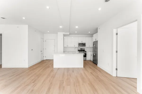 a view of kitchen with kitchen island wooden floors appliances and cabinets