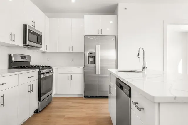 a kitchen with stainless steel appliances granite countertop a refrigerator a stove and a sink