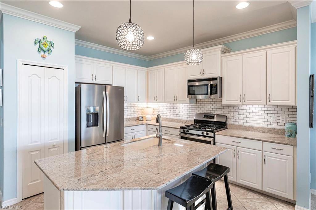 4565 Waterscape Lane Fort Myers, FL 33966 - Photo 9 of 42 Kitchen featuring stainless steel appliances, crown molding, white cabinets, and a sink