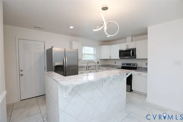 a kitchen with stainless steel appliances granite countertop a refrigerator a stove a sink and a microwave