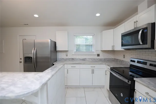 a kitchen with stainless steel appliances granite countertop a sink stove microwave and refrigerator