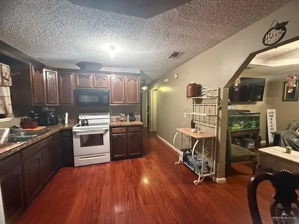 a kitchen with granite countertop a stove a sink and wooden floors
