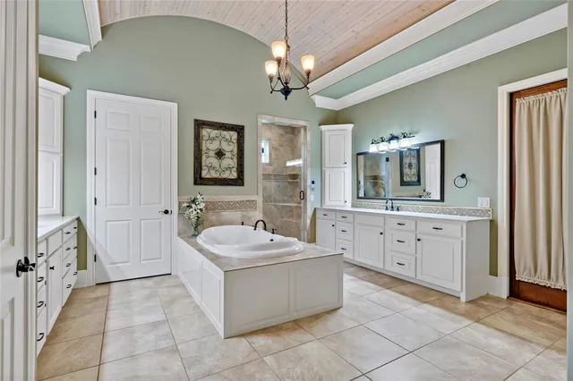 a spacious bathroom with a double vanity sink a mirror a bathtub and a window
