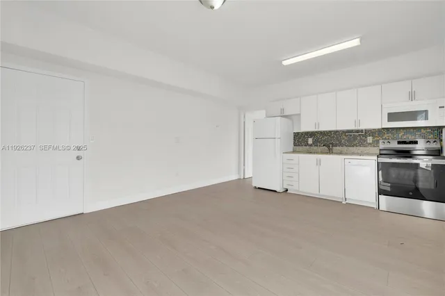 a view of a kitchen with white cabinets and stainless steel appliances