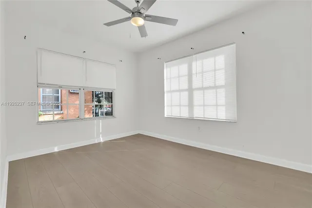 an empty room with windows and fan