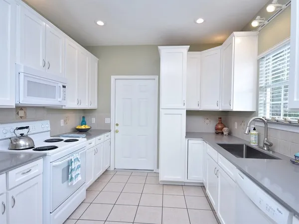 a kitchen with granite countertop white cabinets stainless steel appliances and a sink