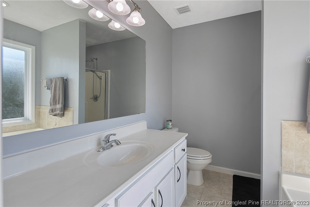244 Rockingham Street Spring Lake, NC 28390 - Photo 24 of 34 a bathroom with a granite countertop sink a toilet and a mirror