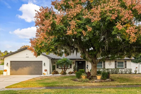 a front view of a house with garden and trees