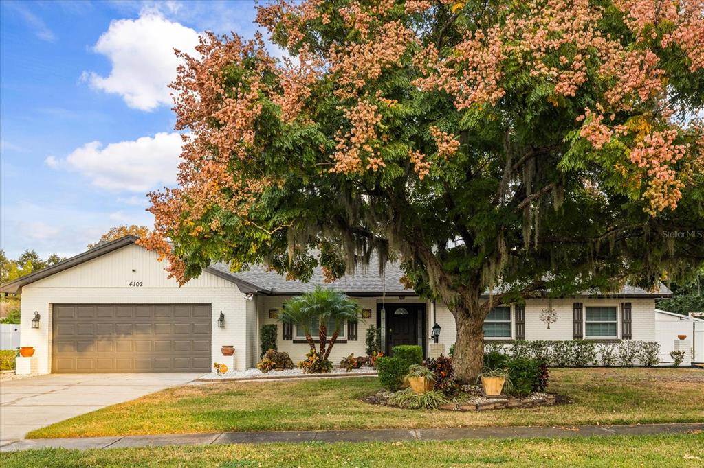 a front view of a house with garden and trees