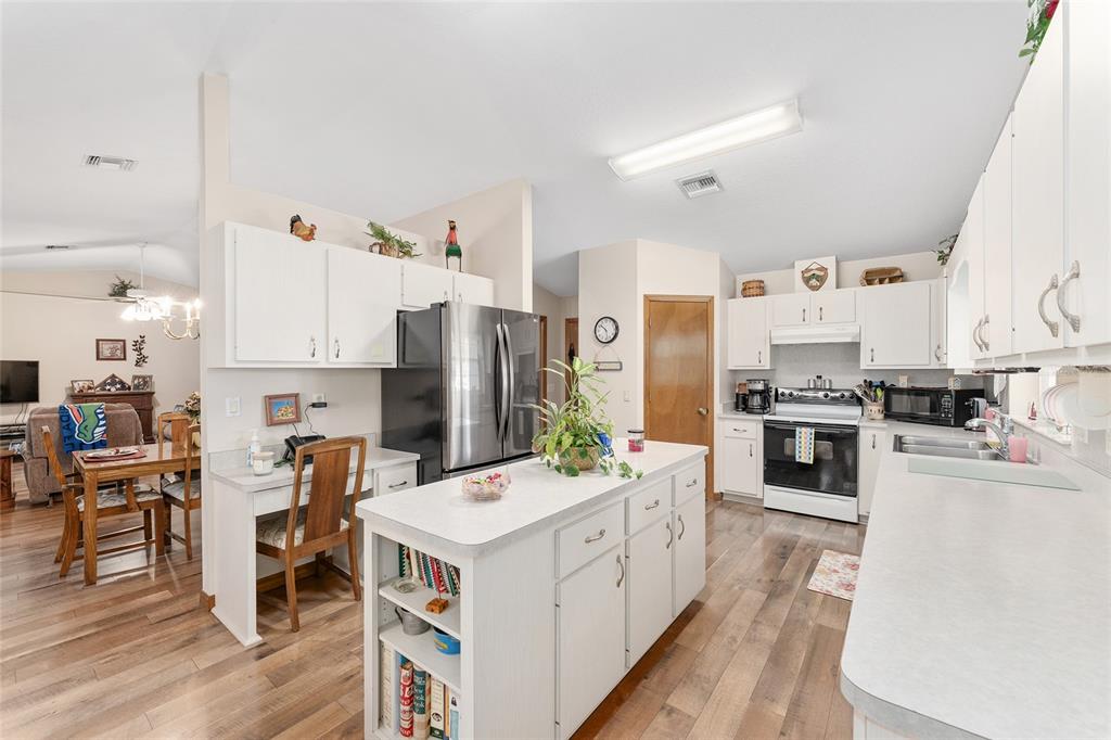 12681 Southeast 54th Avenue Belleview, FL 34420 - Photo 20 of 46 a kitchen with stainless steel appliances kitchen island granite countertop a refrigerator a stove top oven a sink dishwasher and white cabinets with wooden floor