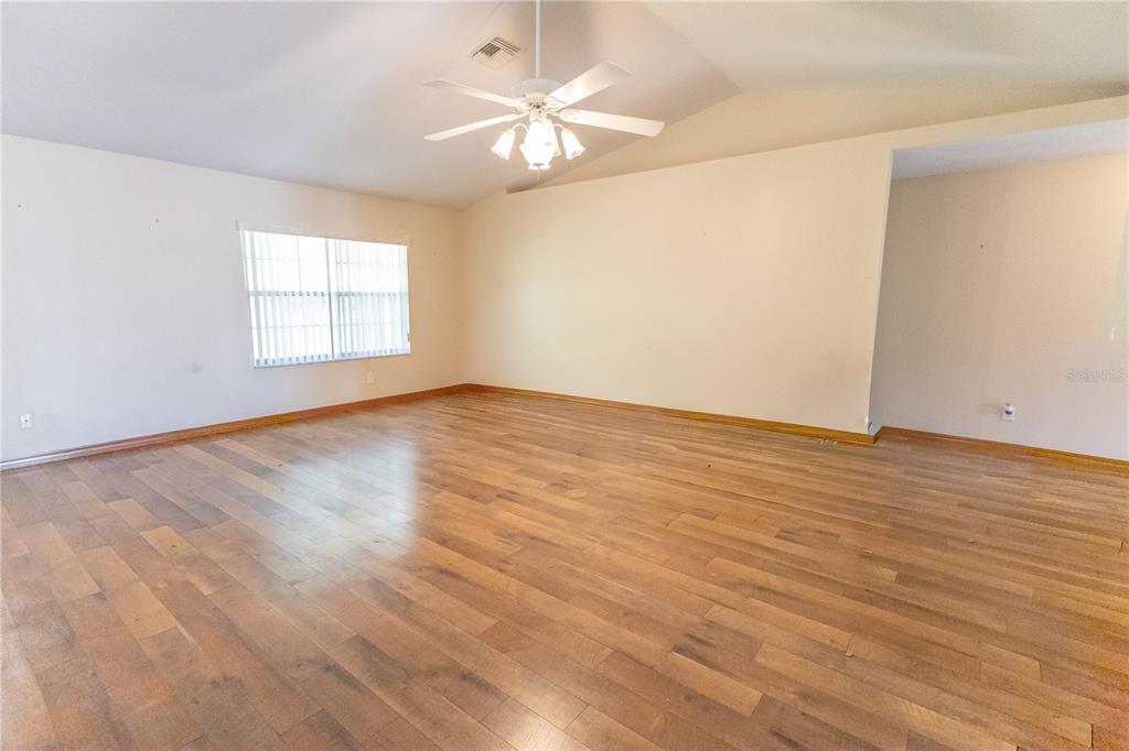12681 Southeast 54th Avenue Belleview, FL 34420 - Photo 23 of 46 an empty room with wooden floor and a ceiling fan