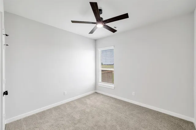 an empty room with window and ceiling fan