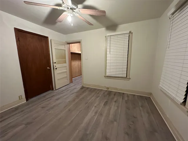 an empty room with wooden floor closet and windows