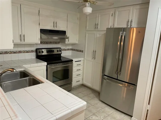 a kitchen with white cabinets and stainless steel appliances