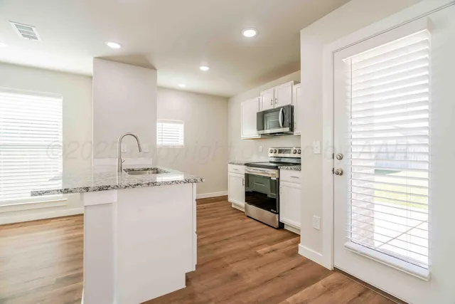 a kitchen with granite countertop a sink stove and refrigerator