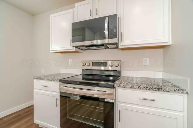 a kitchen with stainless steel appliances granite countertop white cabinets and a stove a oven with white countertops