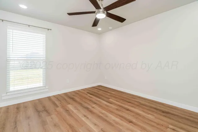 an empty room with a window and a ceiling fan