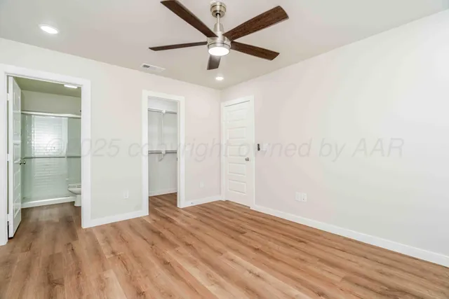 an empty room with wooden floor and a ceiling fan
