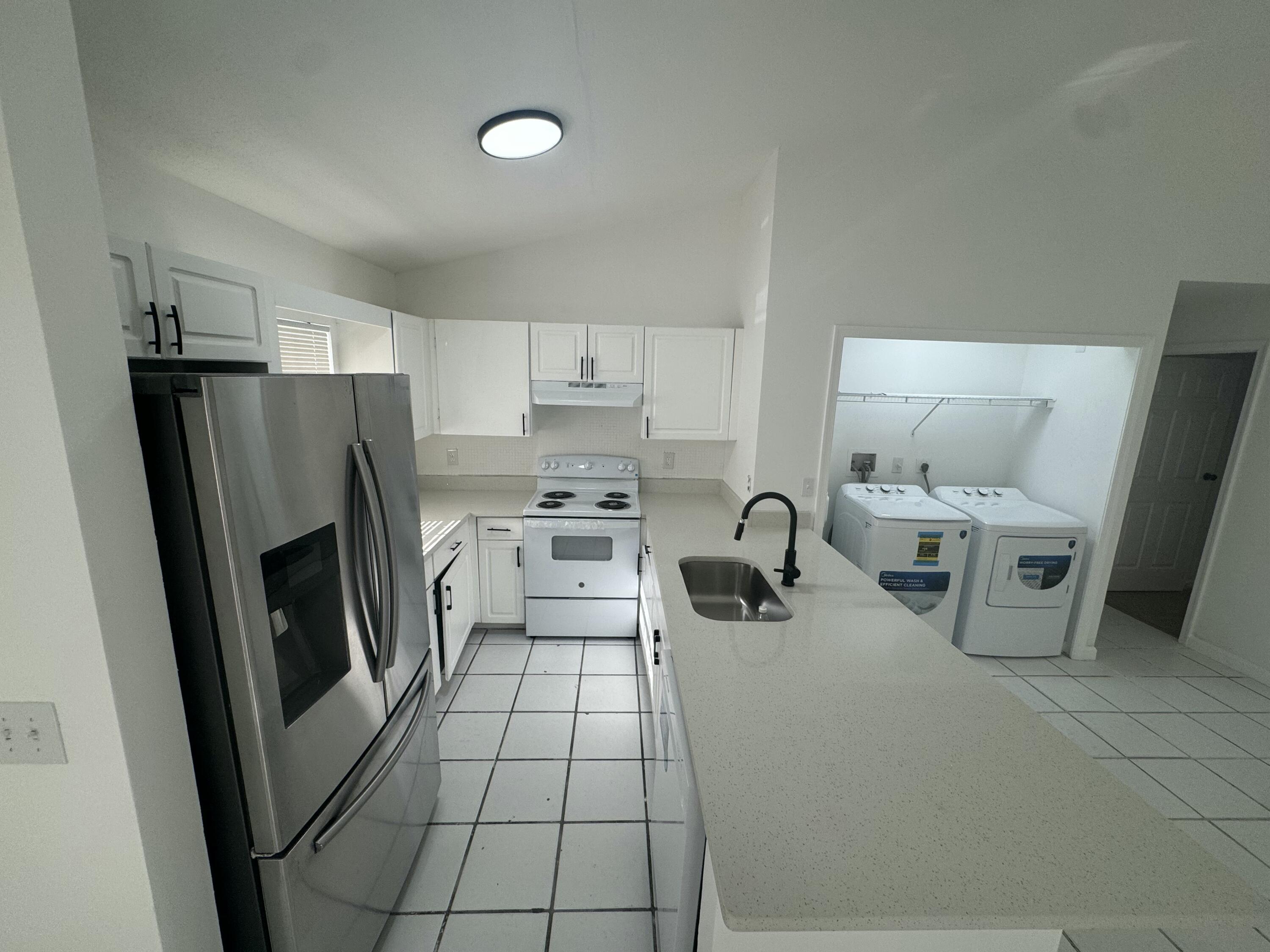 1046 Goldenrod Road, Unit 1048 Wellington, FL 33414 - Photo 6 of 10 a kitchen with a refrigerator a stove a sink a washer and dryer