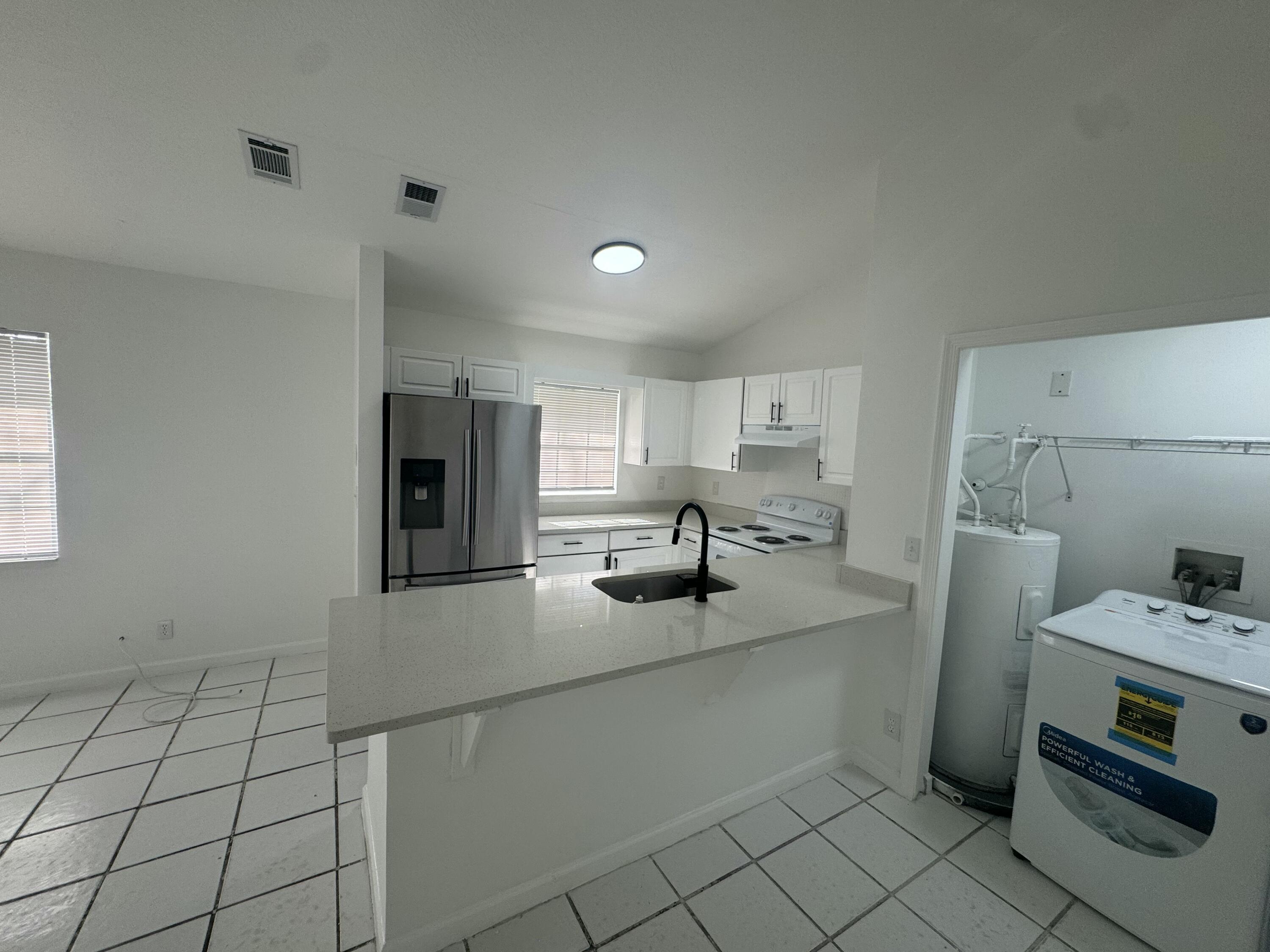 1046 Goldenrod Road, Unit 1048 Wellington, FL 33414 - Photo 8 of 10 a kitchen with refrigerator and cabinets