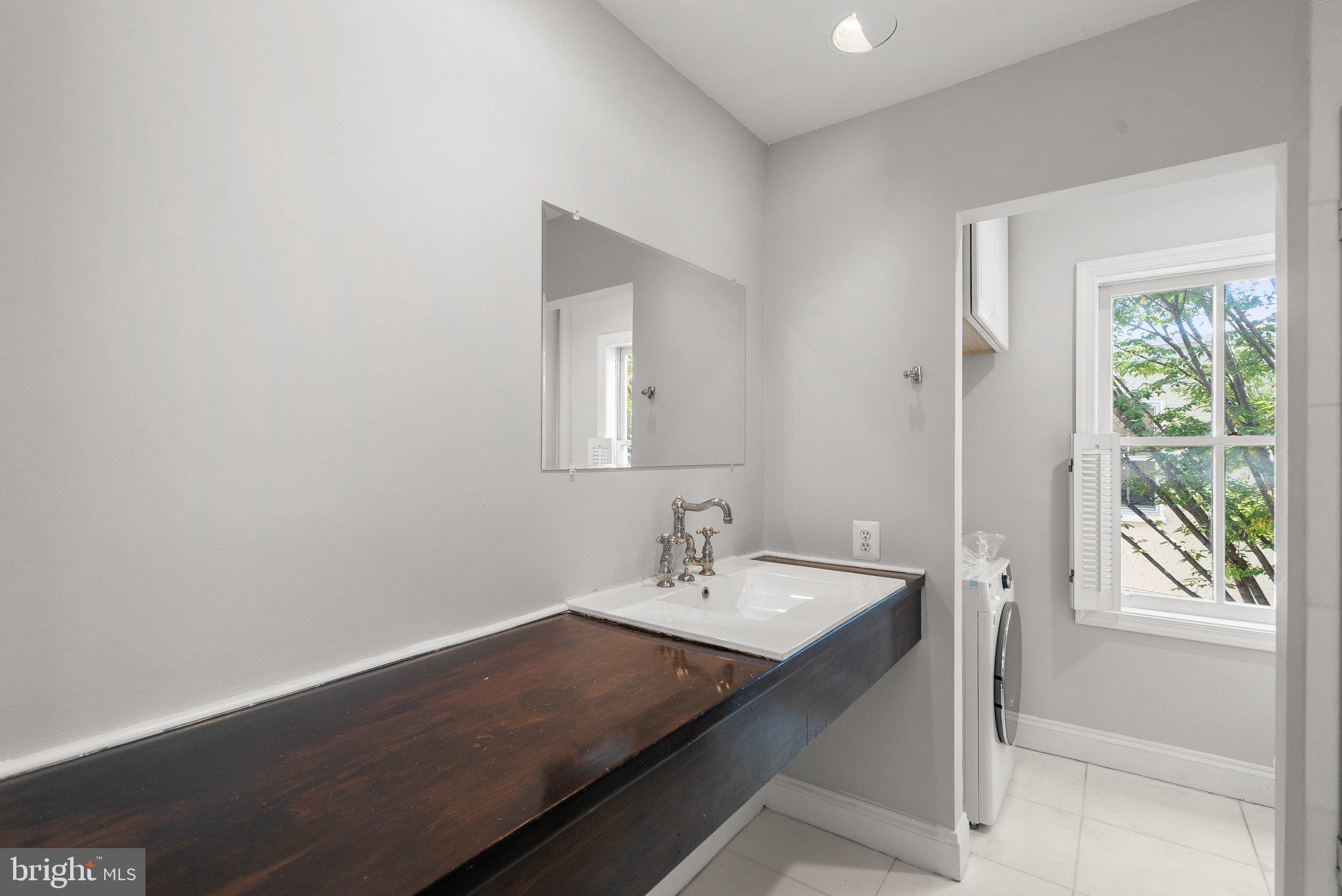 1257 35th Street Northwest Washington, DC 20007 - Photo 17 of 21 a bathroom with a sink a large mirror and a window