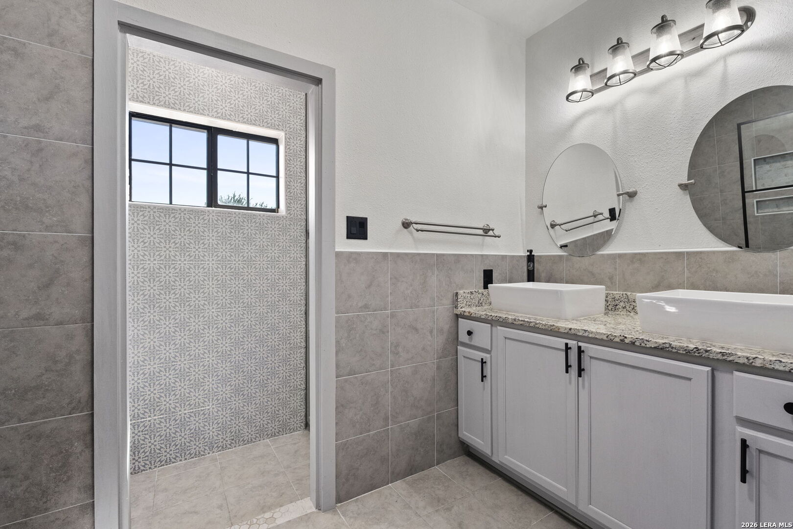 10918 Hunters Way Helotes, TX 78023 - Photo 32 of 49 a bathroom with a granite countertop sink a mirror and shower