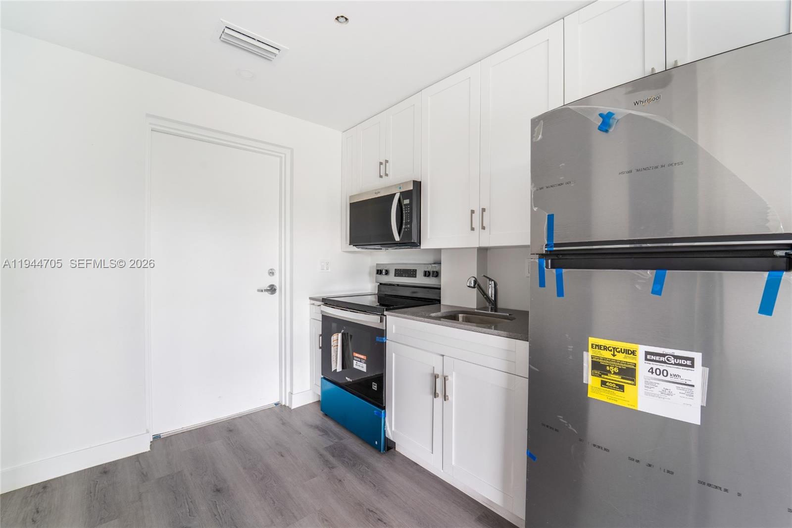 1165 Northwest 8th Avenue, Unit 101 Miami, FL 33136 - Photo 2 of 9 a kitchen with a refrigerator and a stove top oven