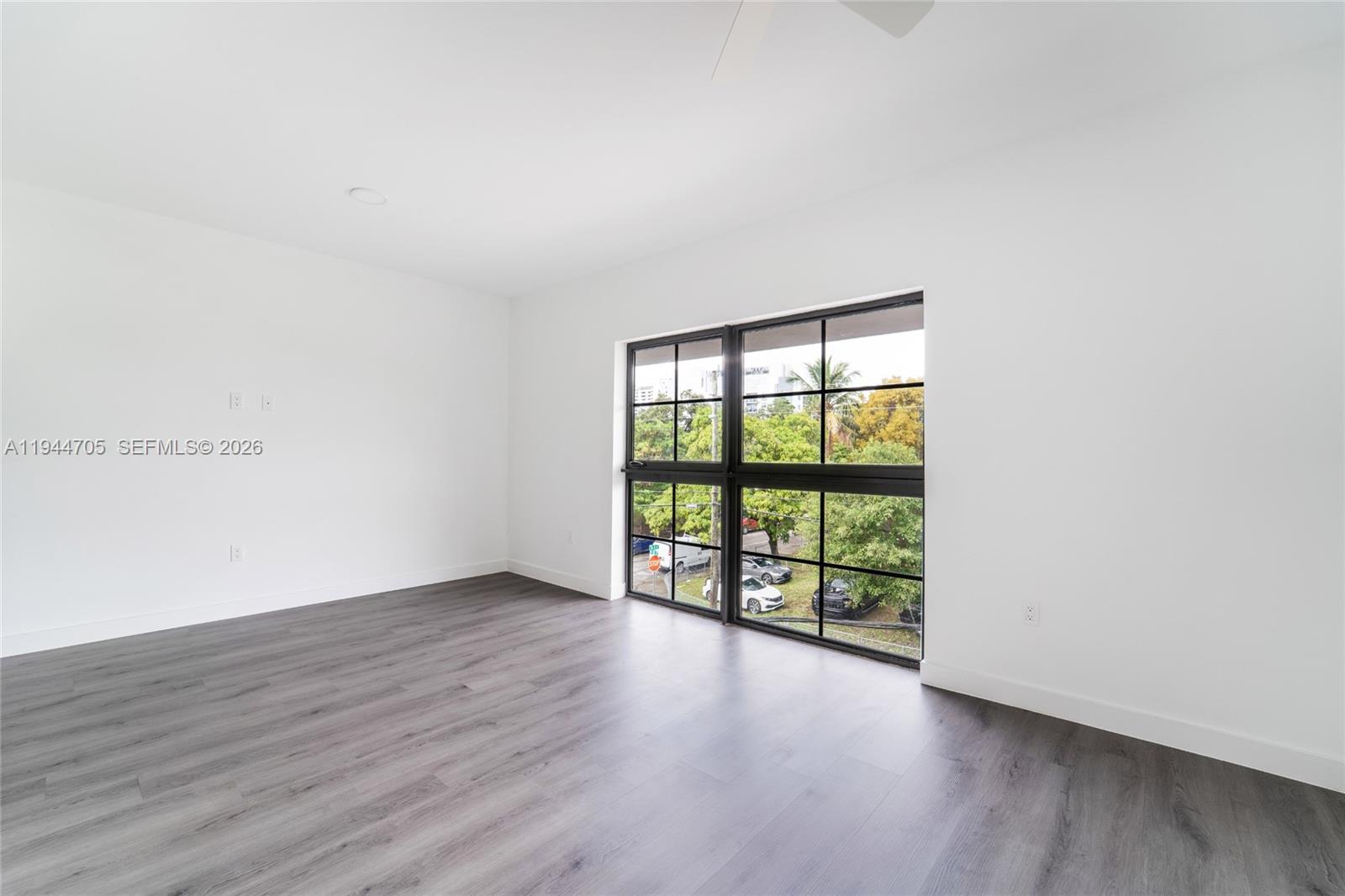 1165 Northwest 8th Avenue, Unit 101 Miami, FL 33136 - Photo 5 of 9 an empty room with wooden floor and windows