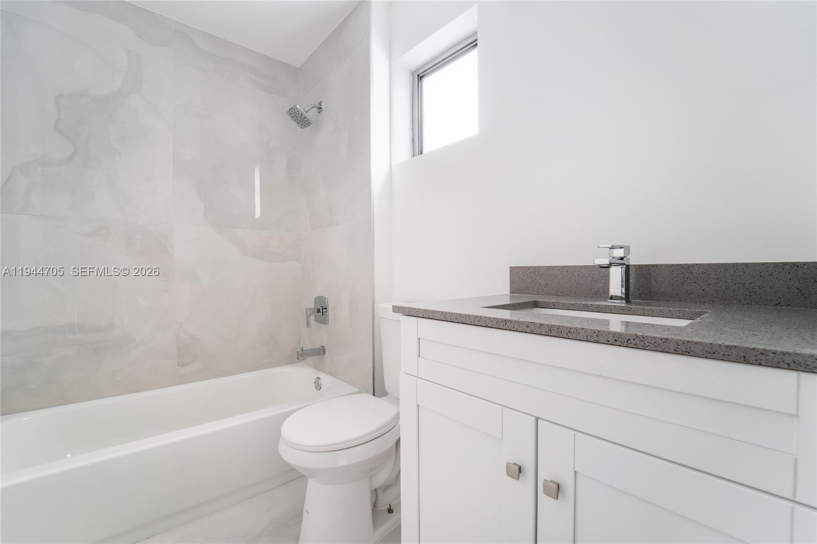 1165 Northwest 8th Avenue, Unit 101 Miami, FL 33136 - Photo 8 of 9 a bathroom with a granite countertop sink a toilet and bathtub