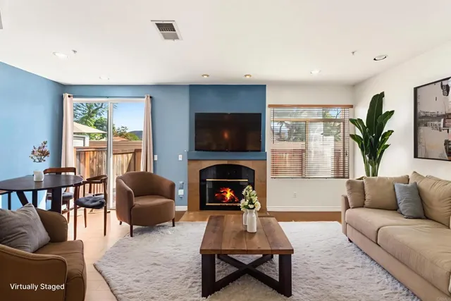 a living room with furniture a rug a fireplace and a large window