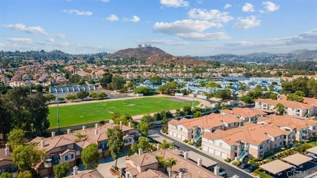 an aerial view of a city with lots of residential buildings ocean and mountain view in back