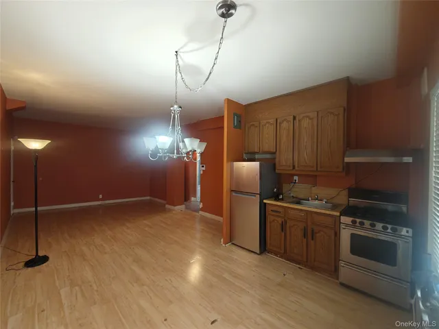 a kitchen with stainless steel appliances granite countertop a stove a refrigerator and a sink with wooden cabinets