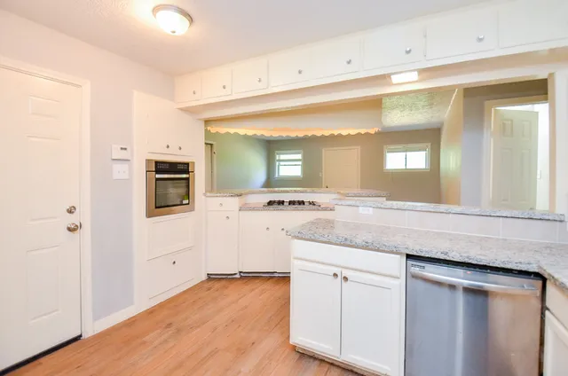 a hall with kitchen island a sink dishwasher a stove and a refrigerator with wooden floor