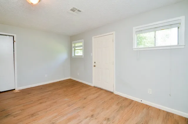 an empty room with wooden floor and windows