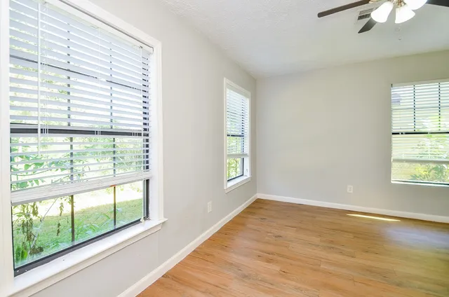 an empty room with wooden floor and windows