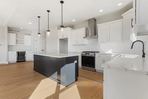 a kitchen with stainless steel appliances granite countertop a sink a stove and a wooden floor