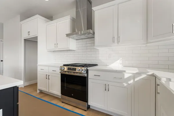 a kitchen with stainless steel appliances granite countertop a sink a stove a refrigerator and white cabinets