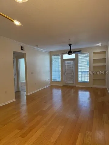 a view of an empty room with window and wooden floor