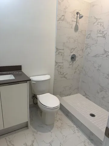 a bathroom with a granite countertop toilet a sink a mirror and vanity